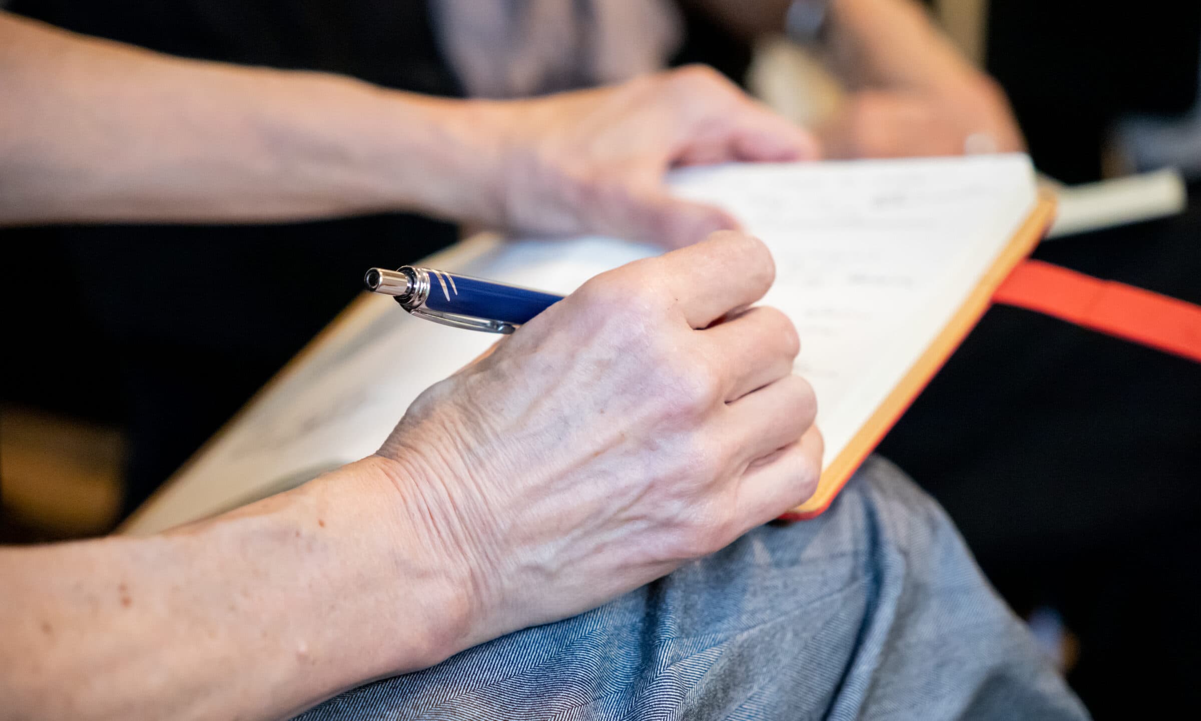 A leader writing reflections in a notebook during a workshop
