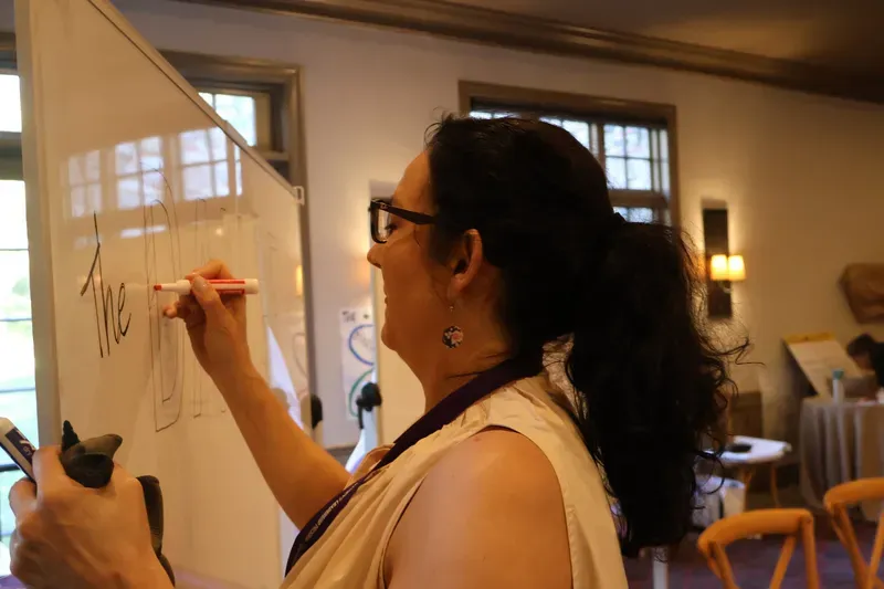 Saffron Samuels hand-lettering a program whiteboard
