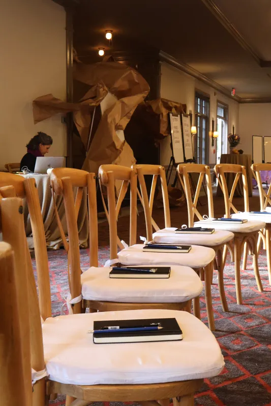 Chairs set with notebooks beneath a brown-paper installation