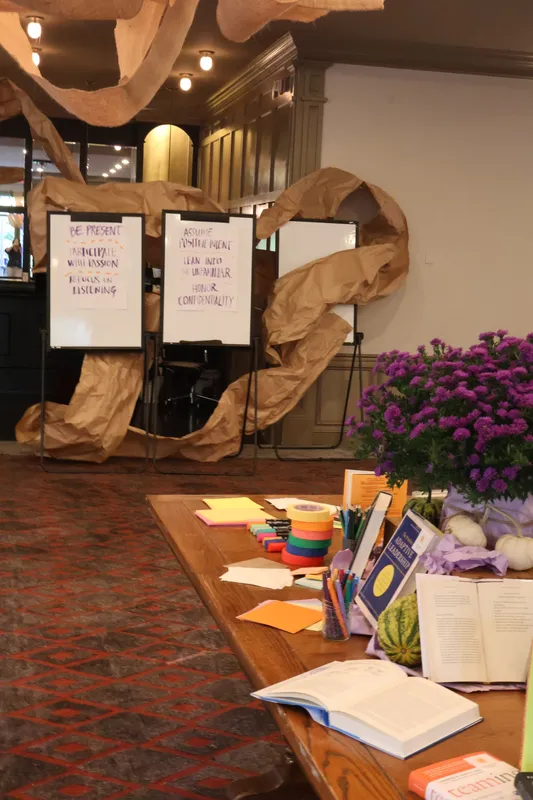 Flip charts and materials table framed by a brown-paper installation